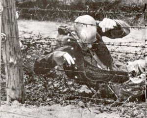 The body of an inmate sits motionless in death after committing suicide on an electrified fence at Auschwitz.