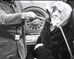 An elderly Polish Jewish woman is shown being humiliated and brutalized by a Nazi SS officer in Poland in 1940.